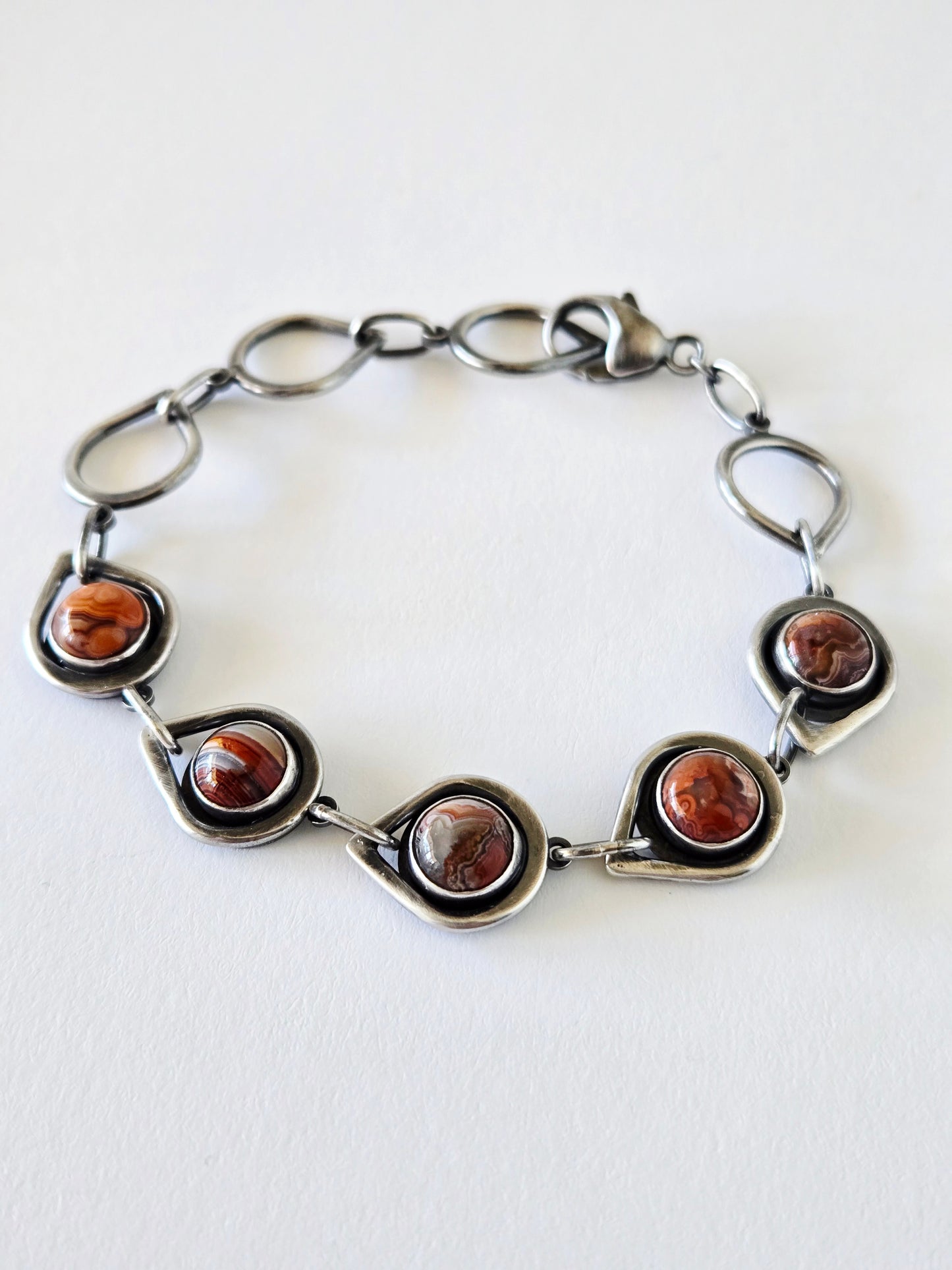 Silver bracelet with red and orange stones on a white background