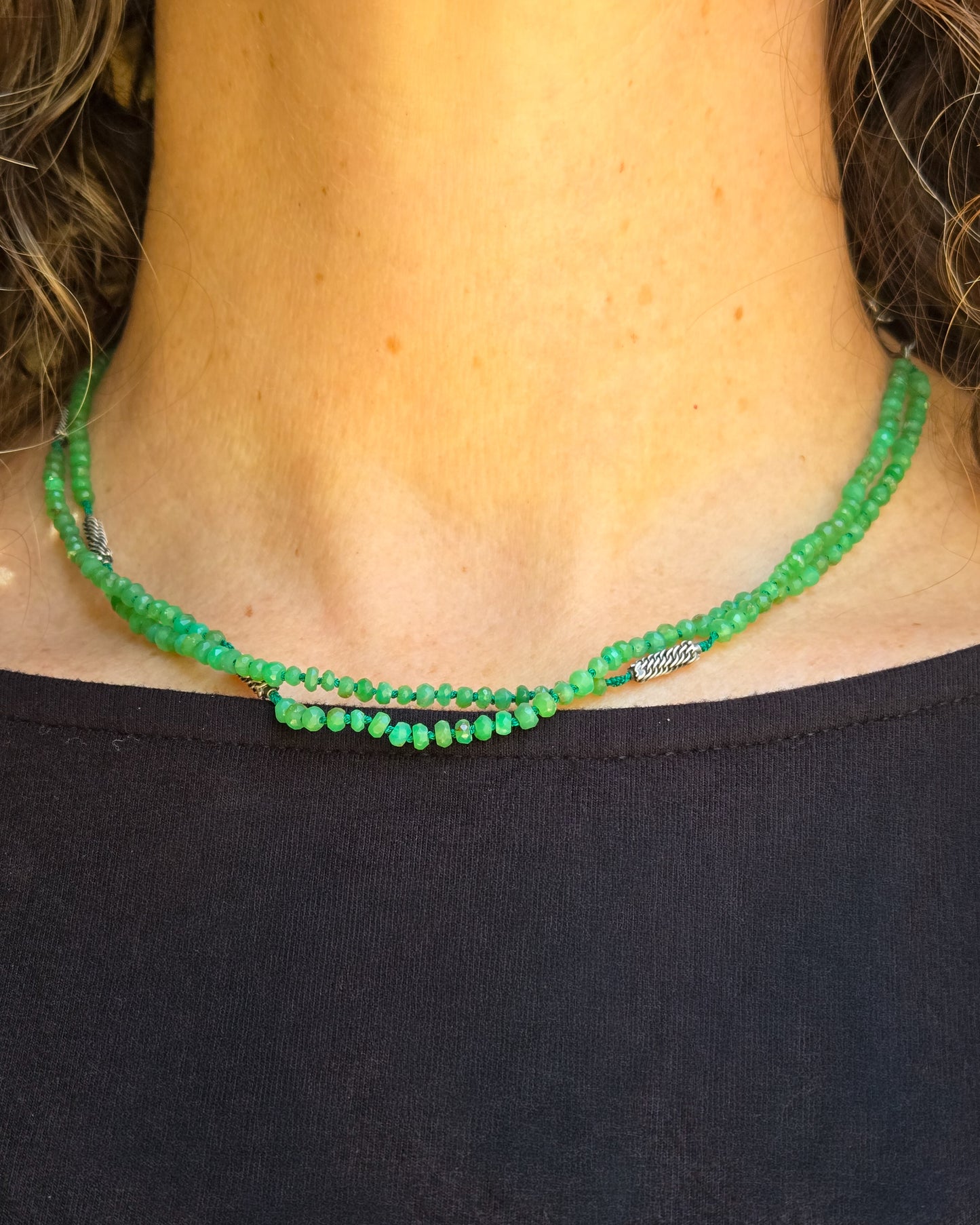 Green beaded necklace worn on a person wearing a black top