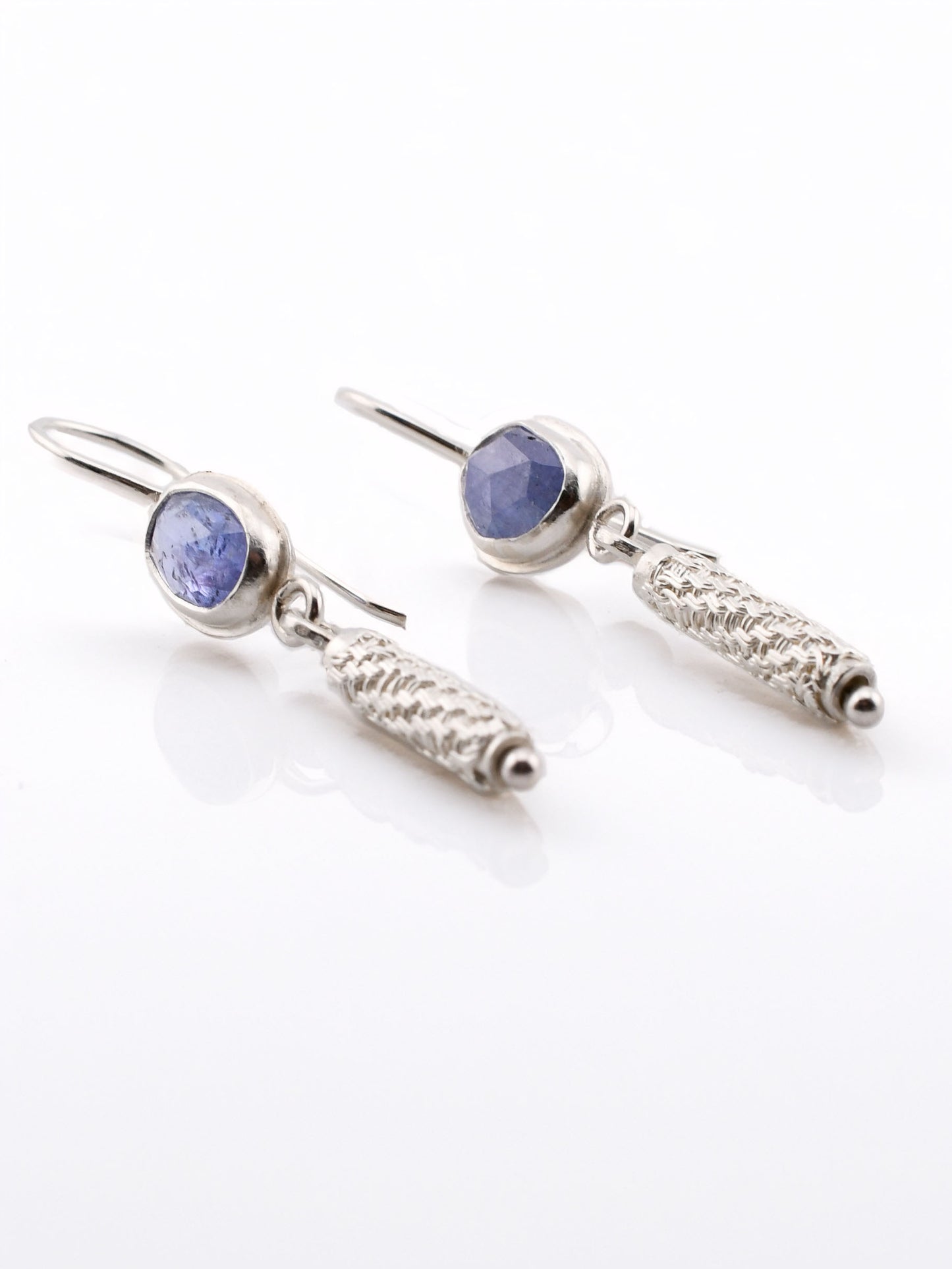 Pair of silver earrings with blue gemstones on a white background