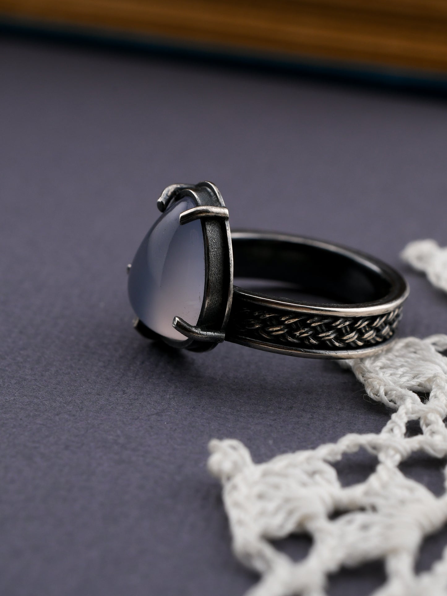 Lavender stone ring with a textured band on a textured surface