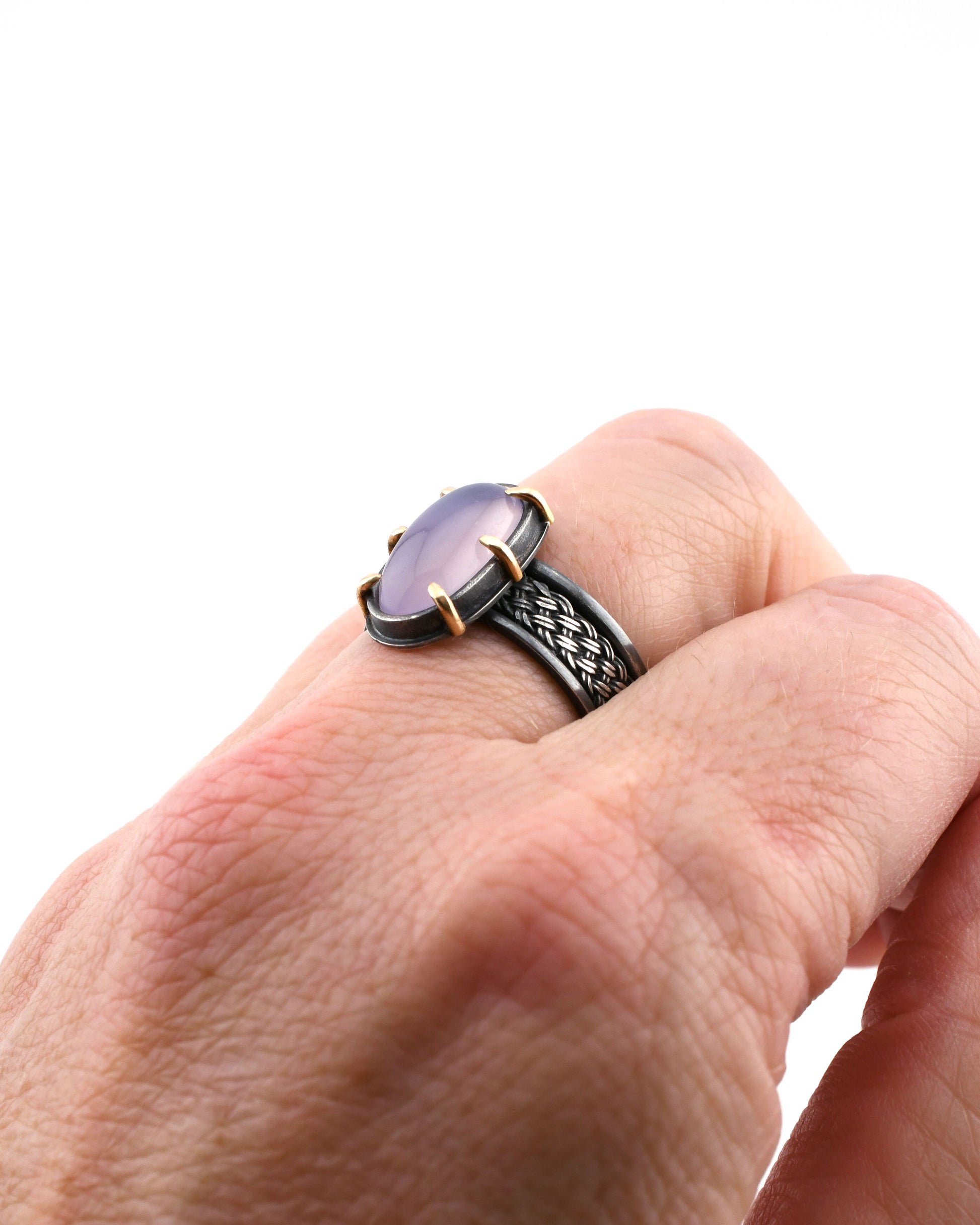Hand wearing a ring with a purple stone on a white background