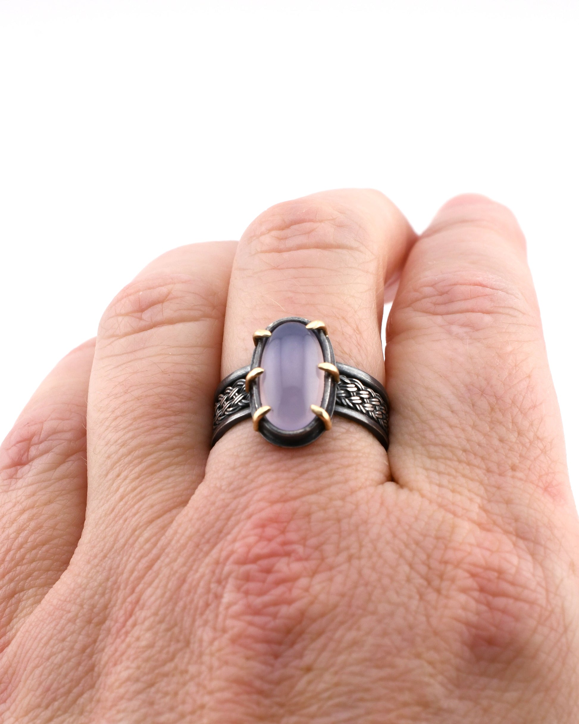 Hand wearing a ring with a purple gemstone on a white background