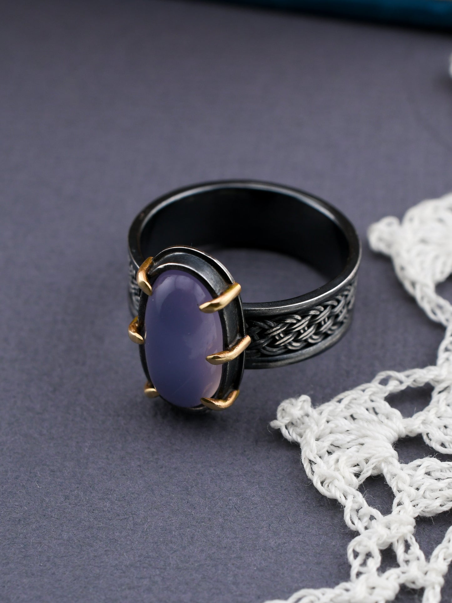 Black ring with a purple stone on a gray surface with white lace
