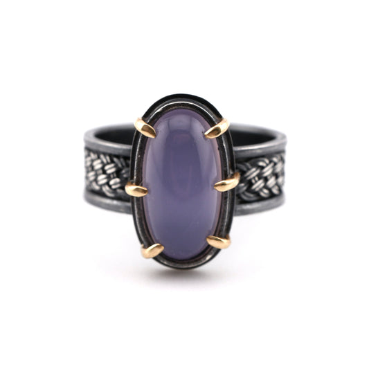 Ring with purple stone and gold accents on a white background