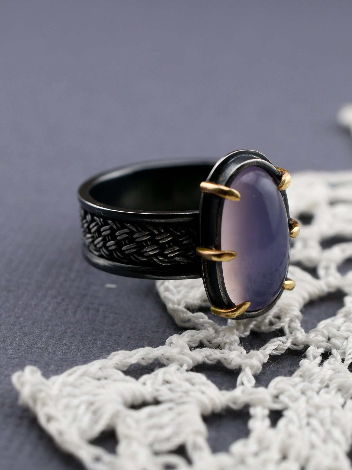 Black ring with a purple stone on a textured surface