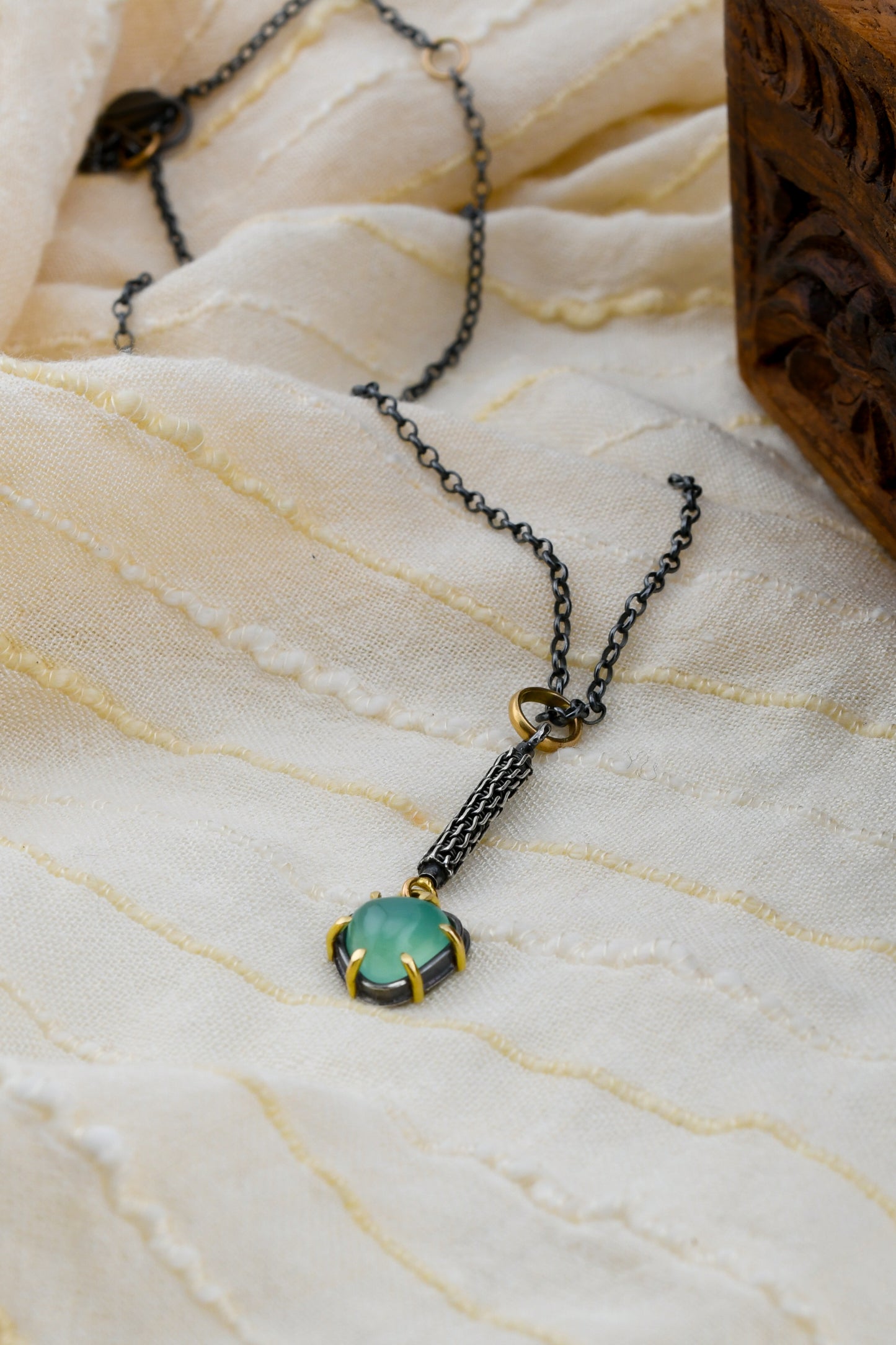 Necklace with a green gemstone pendant on a textured fabric background
