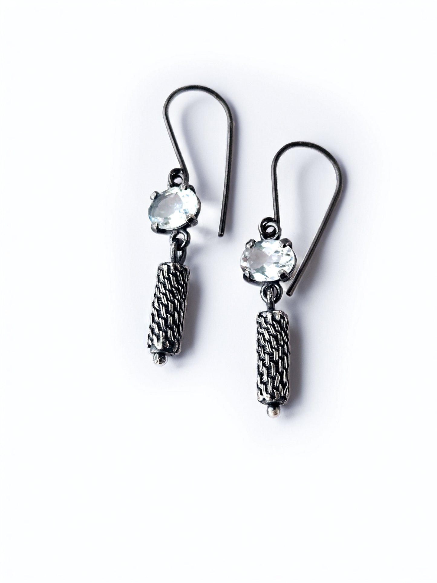 Pair of silver earrings with ice blue gemstones on a white background