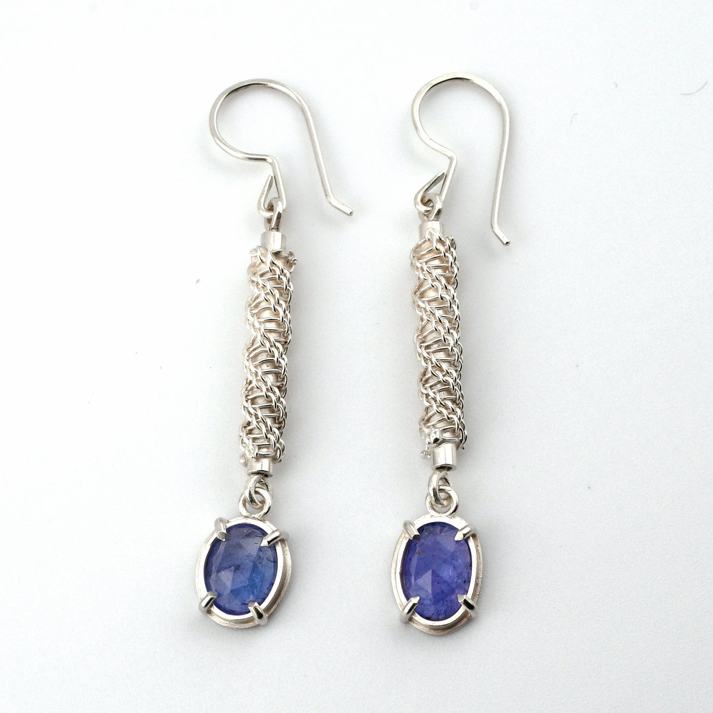 Silver earrings with blue gemstones on a white background