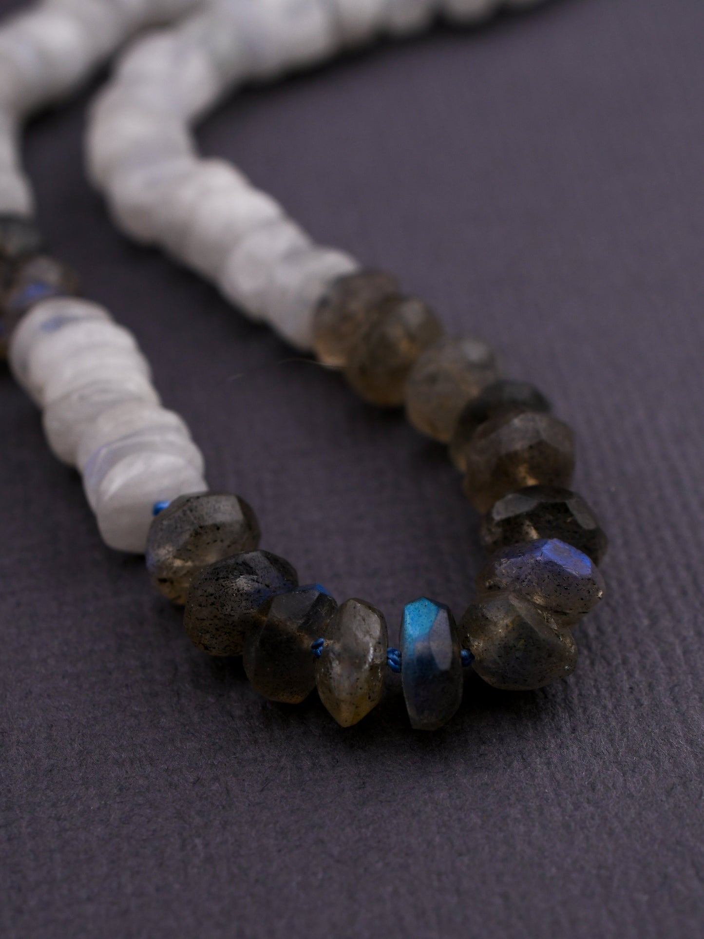 close-up of labradorite beaded necklace on a textured gray background