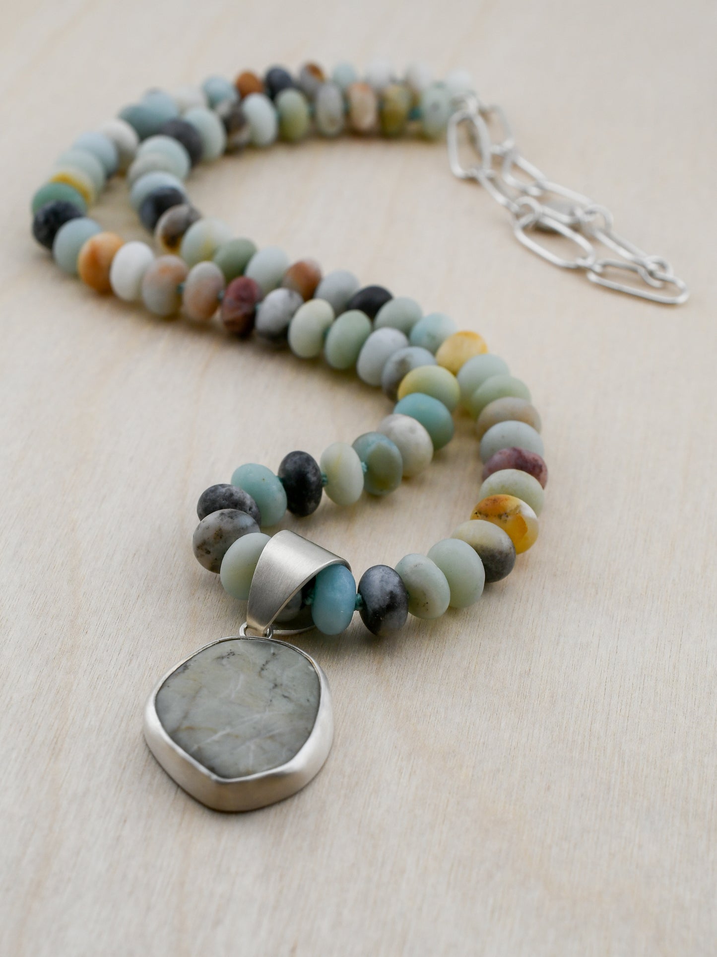 Necklace with multicolored beads and a large stone pendant on a light background