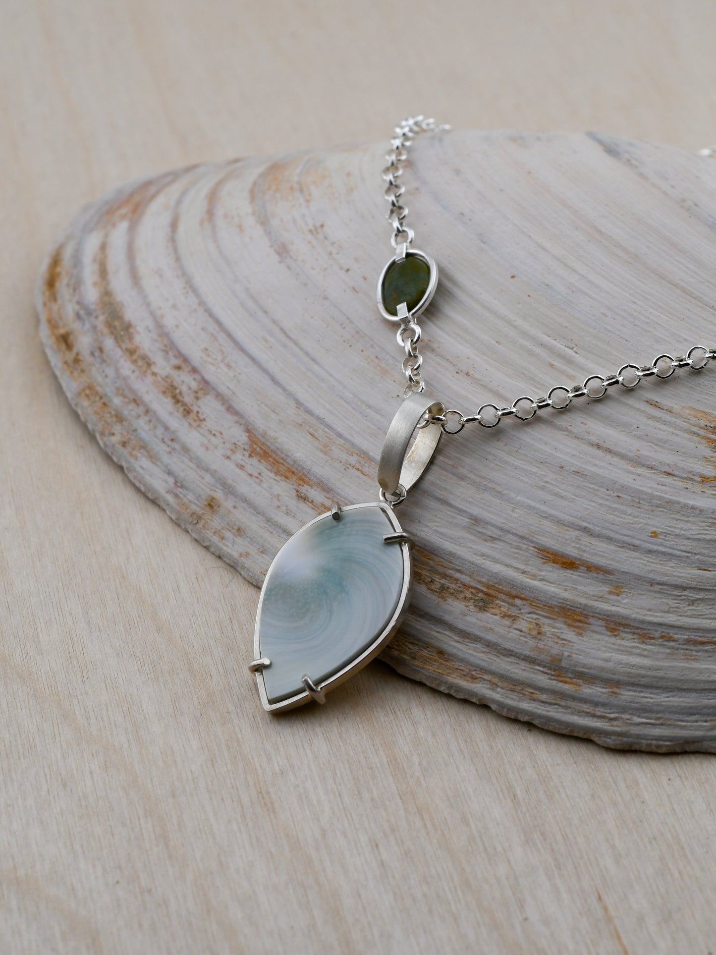 Necklace with a blue shell pendant on a shell background