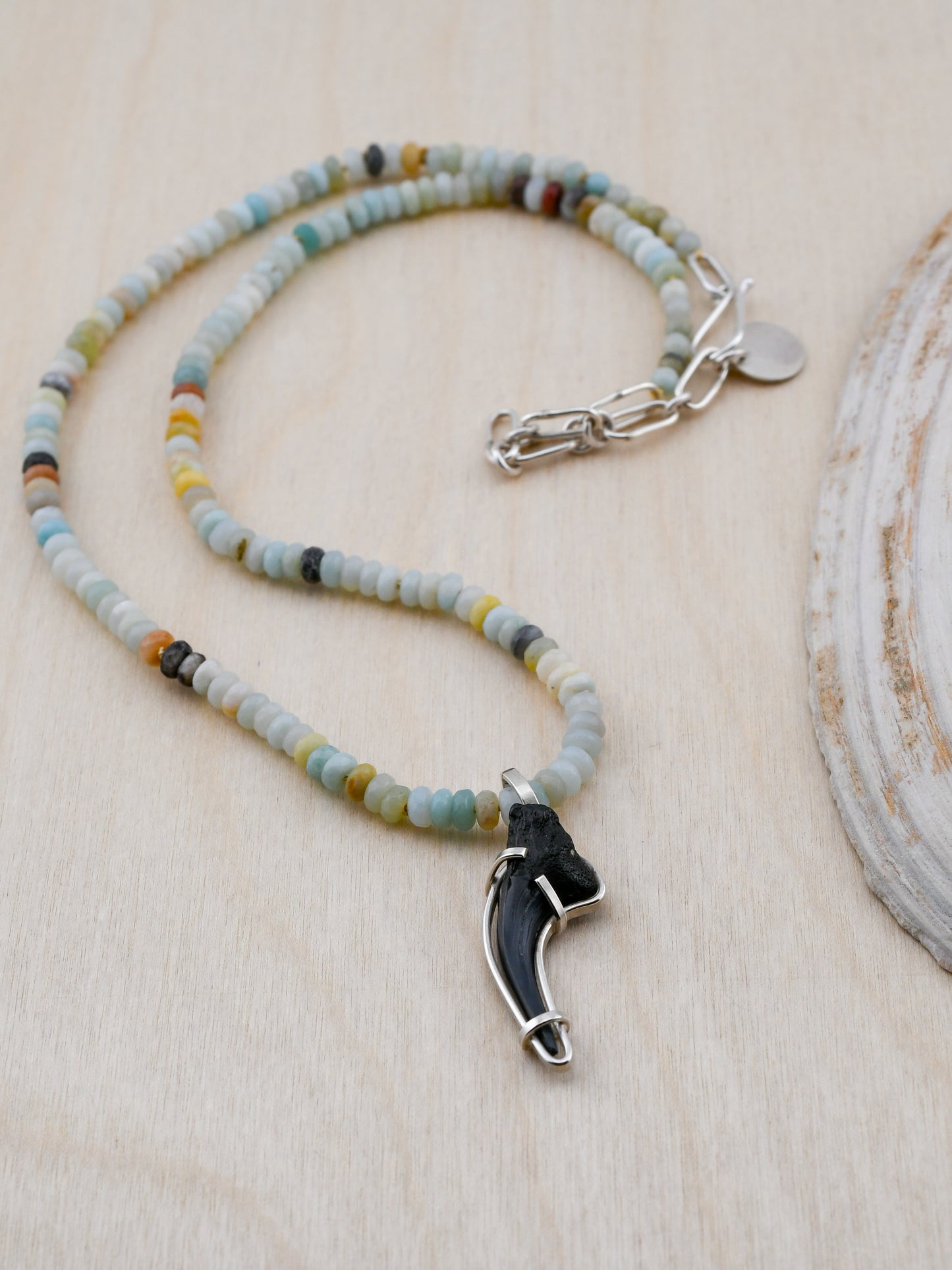 Necklace with beaded chain and unique pendant on a wooden surface
