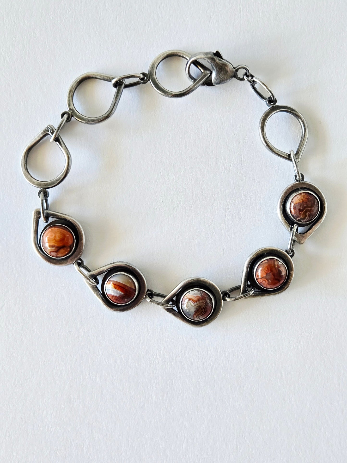 Silver bracelet with teardrop links and 5 circular agates on a white background