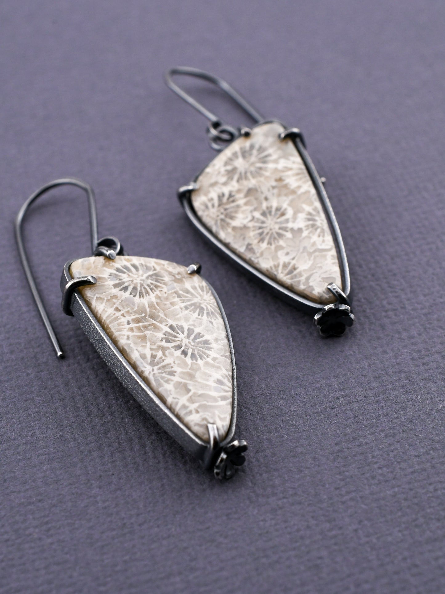 gray and white stone earrings on a dark background