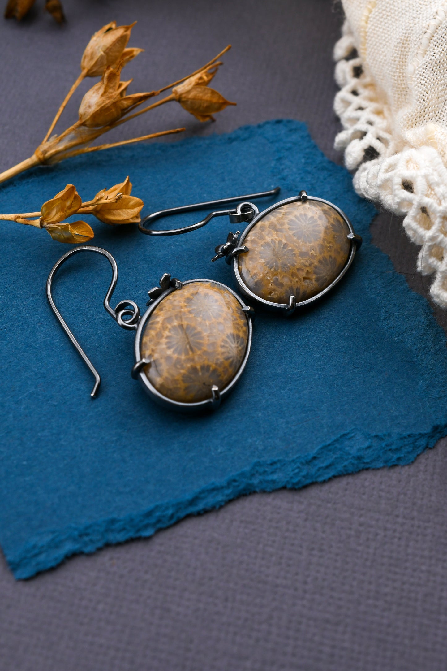 Pair of earrings with floral stones on a blue surface