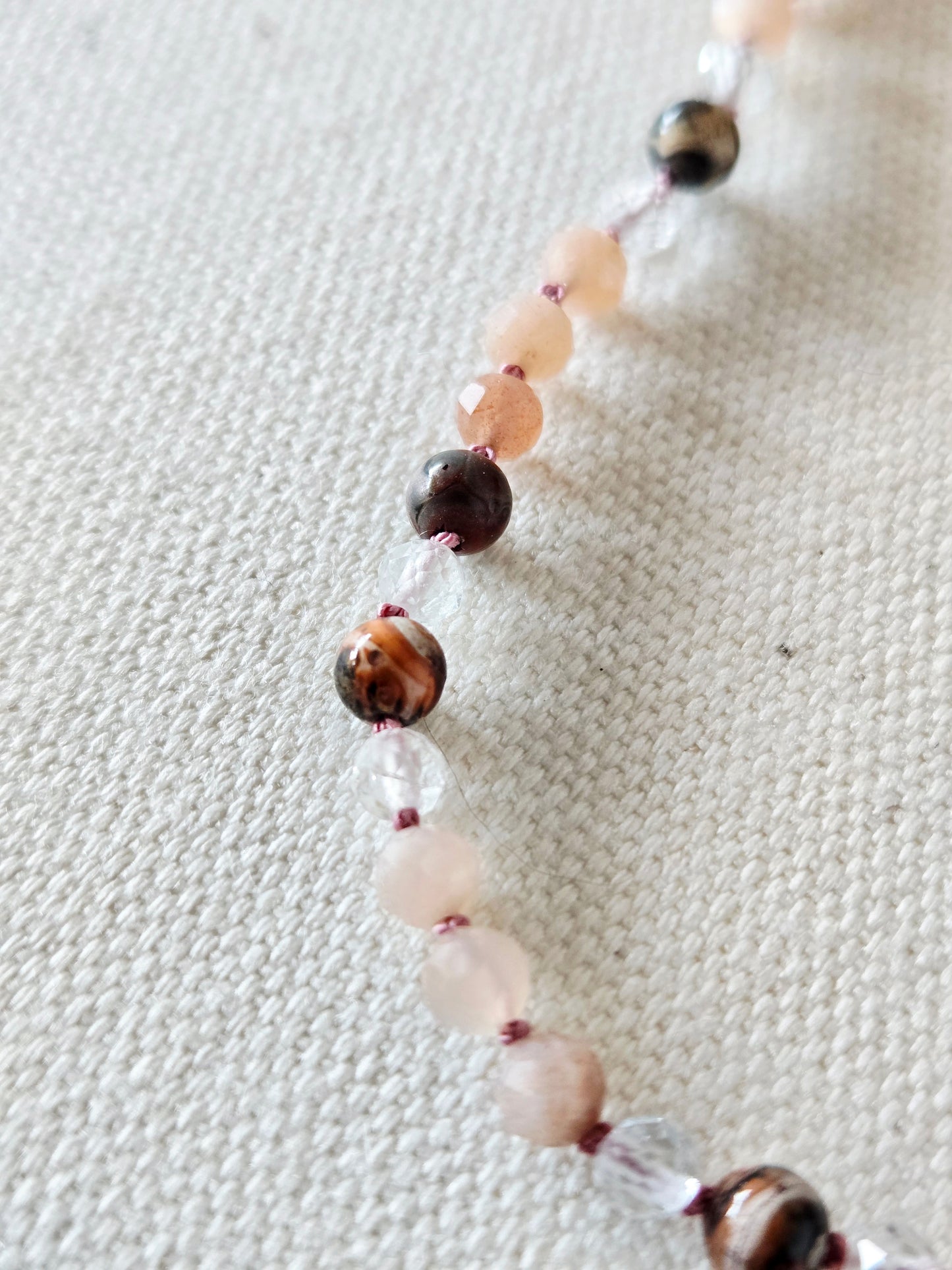 Necklace with multicolored beads on a textured fabric background