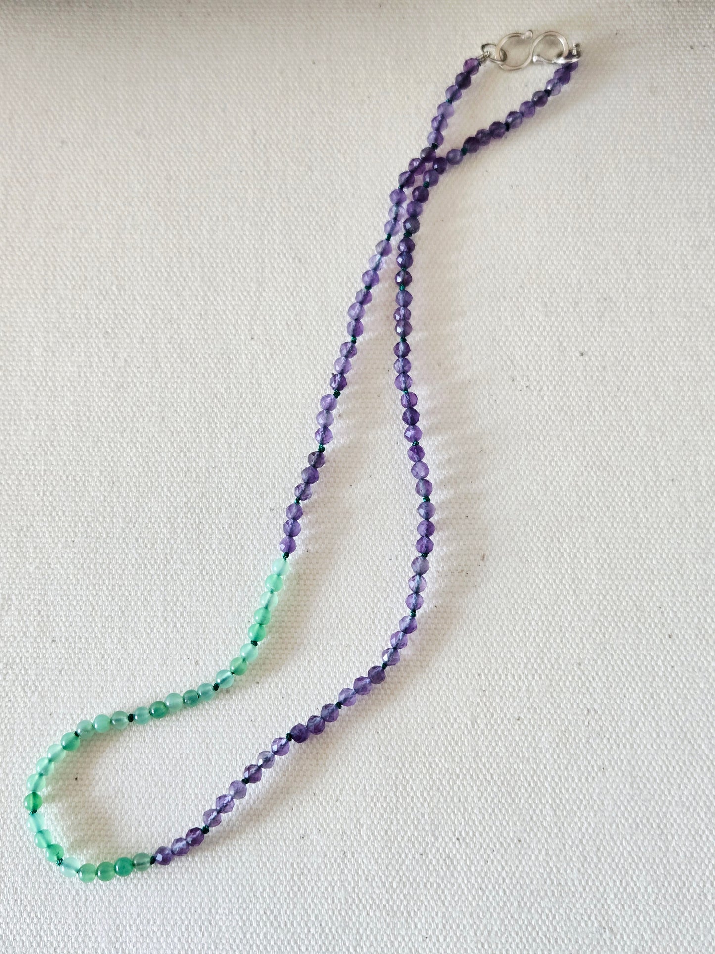 Beaded necklace with green and purple beads on a white background