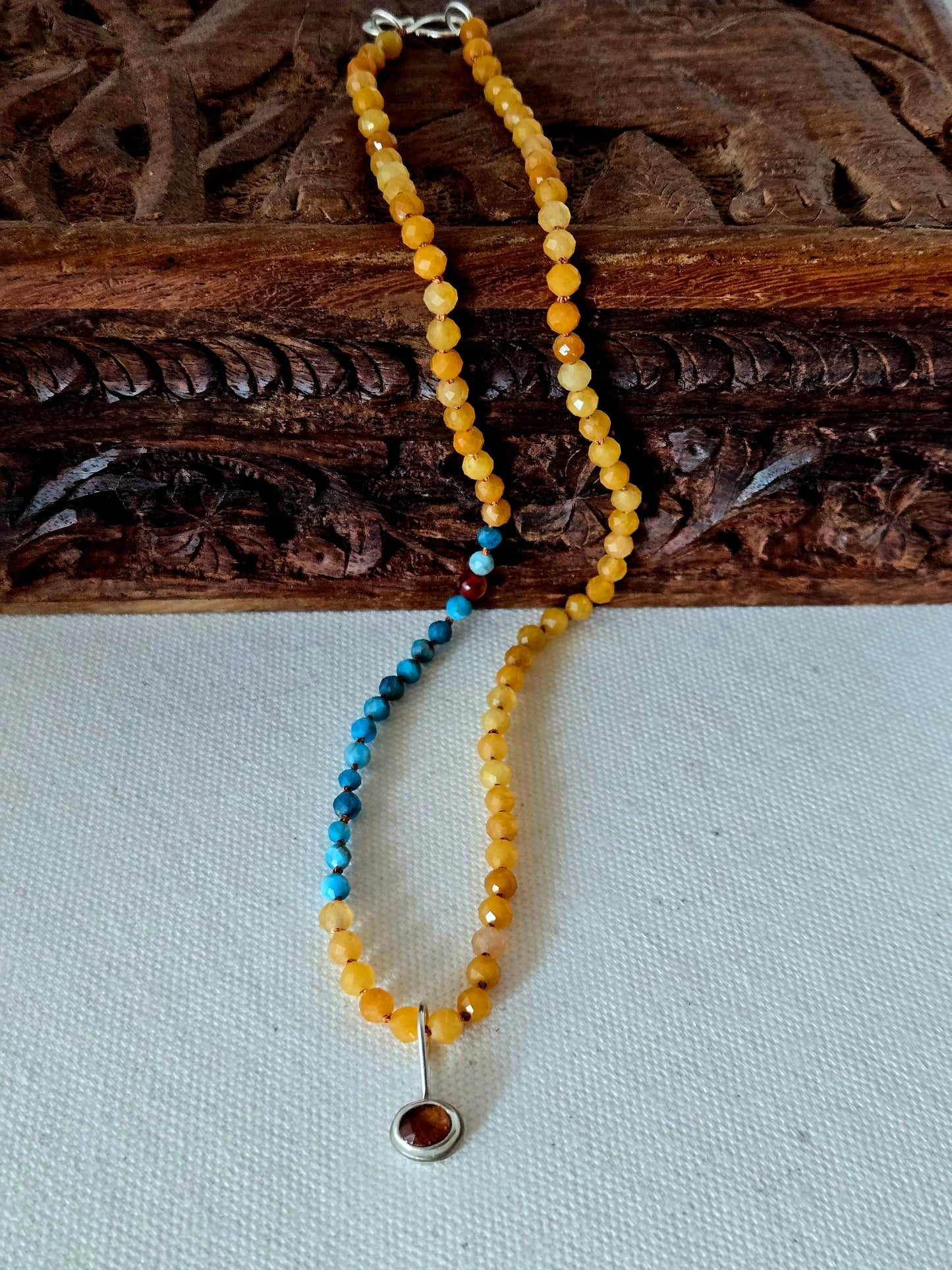 Beaded necklace with a pendant on a wooden surface