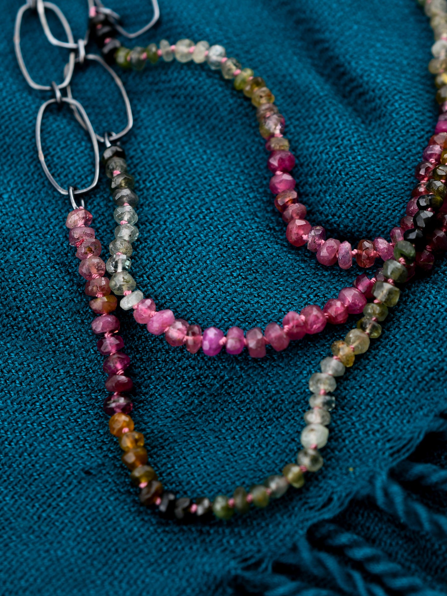 Multicolored beaded necklace on a blue textured fabric background