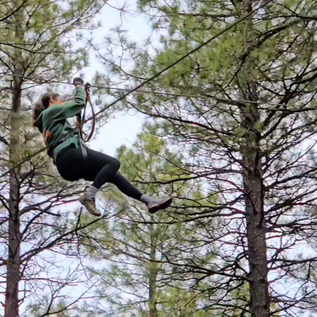 the author ziplining through pine trees