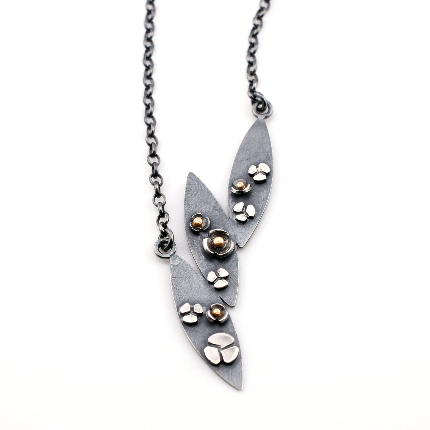 3 leaf necklace with flowers in black silver and gold on a white background