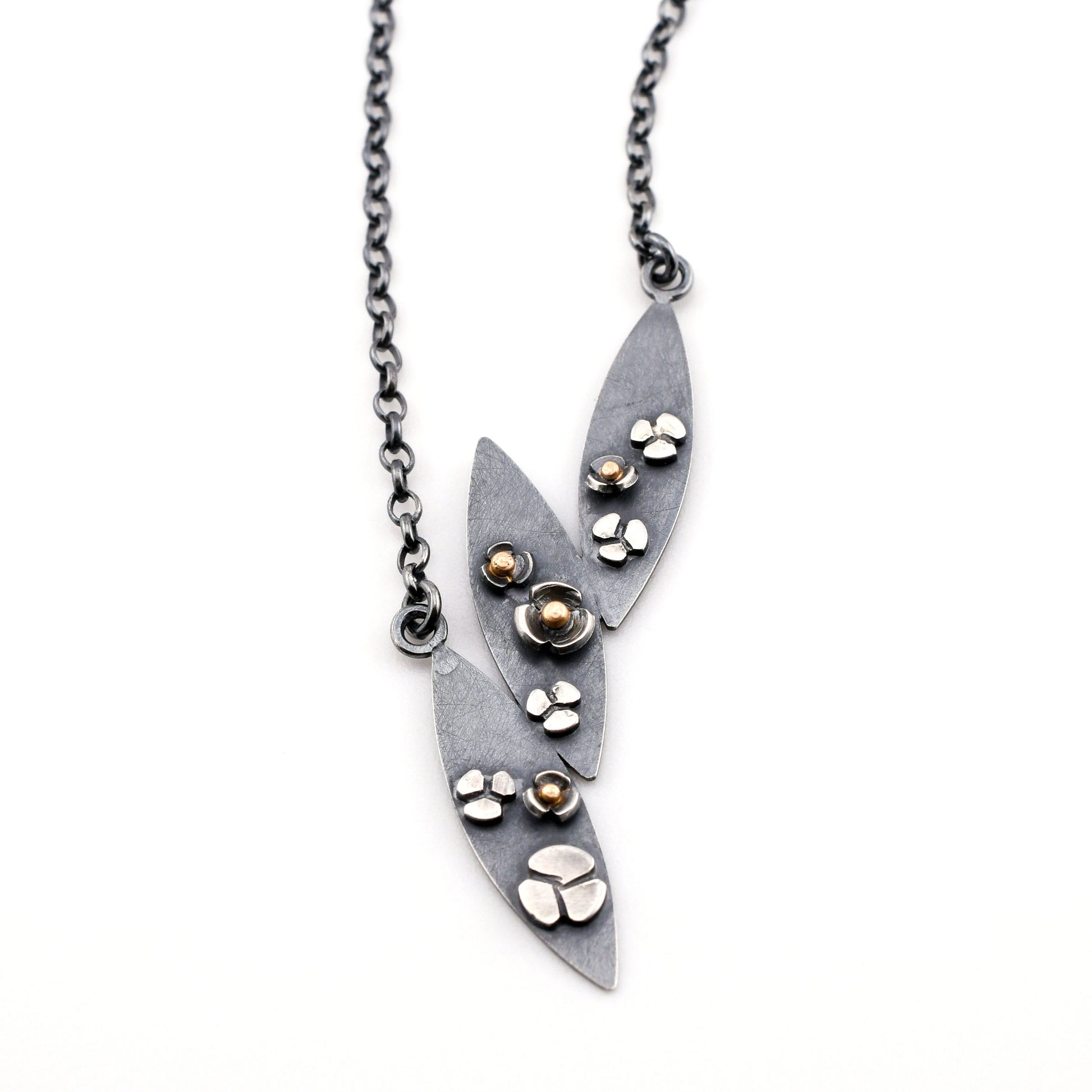 3 leaf necklace with flowers in black silver and gold on a white background