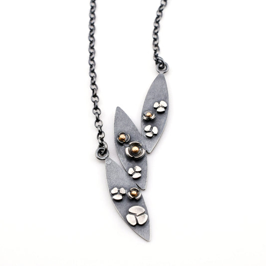 3 leaf necklace with flowers in black silver and gold on a white background