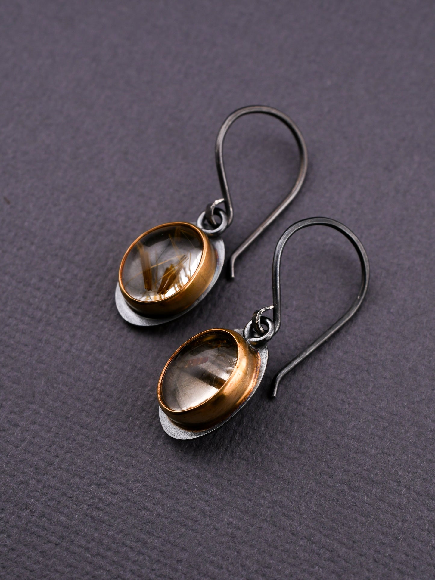 Pair of earrings with clear gemstones on a gray textured background