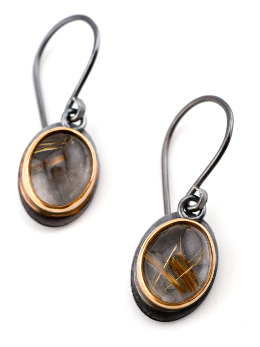 Pair of earrings with oval  rutilated quartz set in gold bezels on a white background