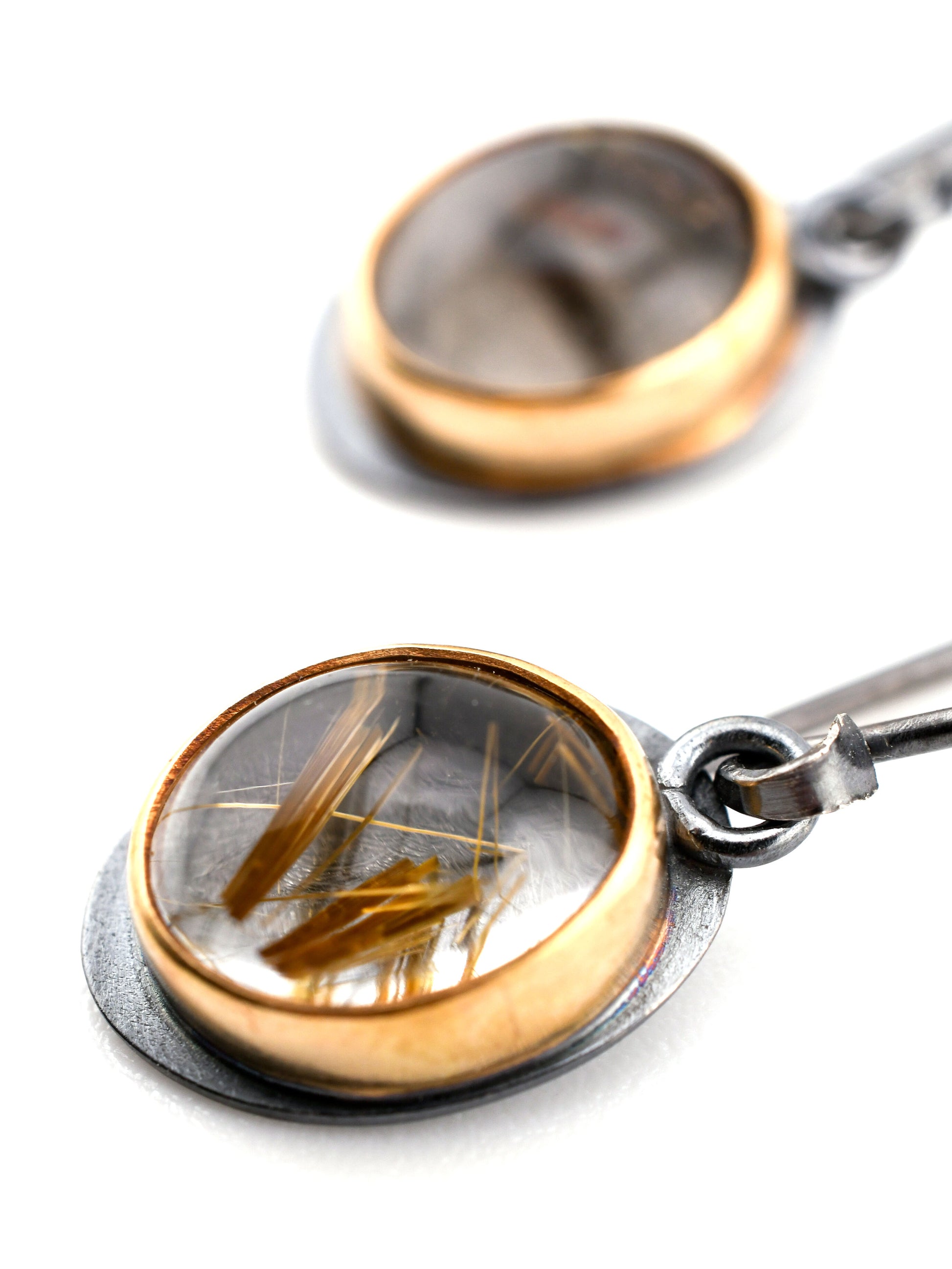 Close-up of a rutilated quartz earrings on a white background