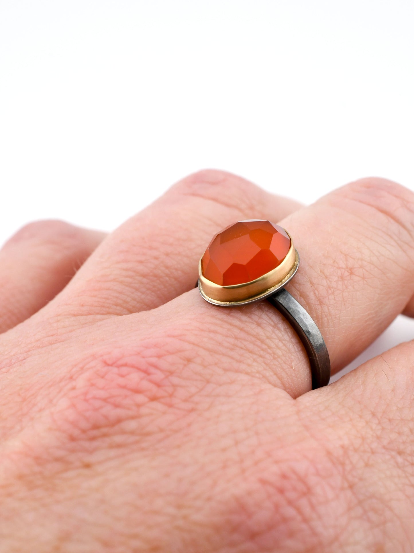 Ring with a red stone on a finger against a white background