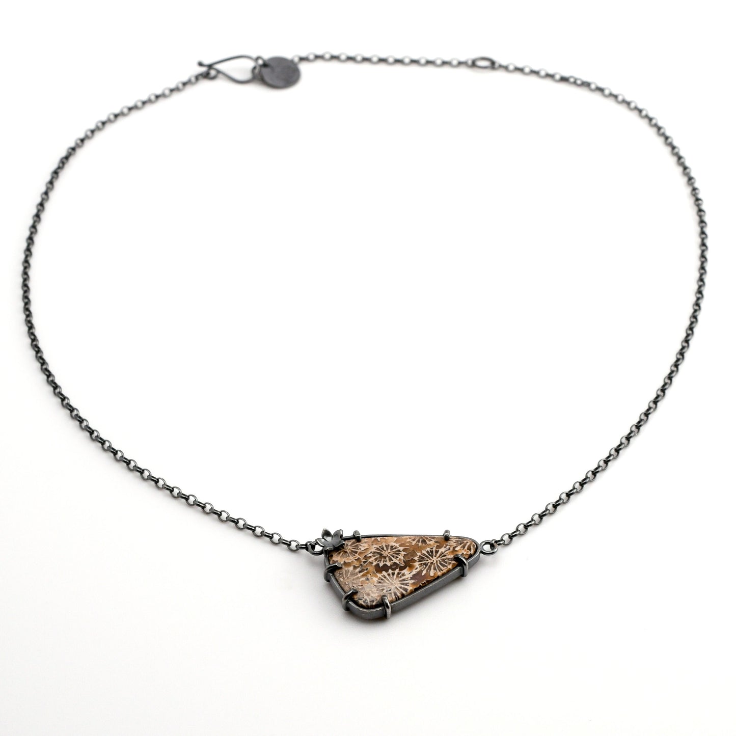 Necklace with a triangular fossilized coral pendant on a white background
