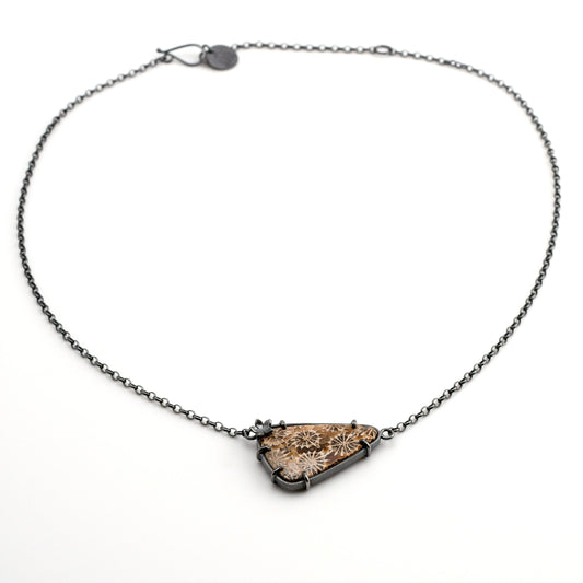 Necklace with a triangular fossilized coral pendant on a white background