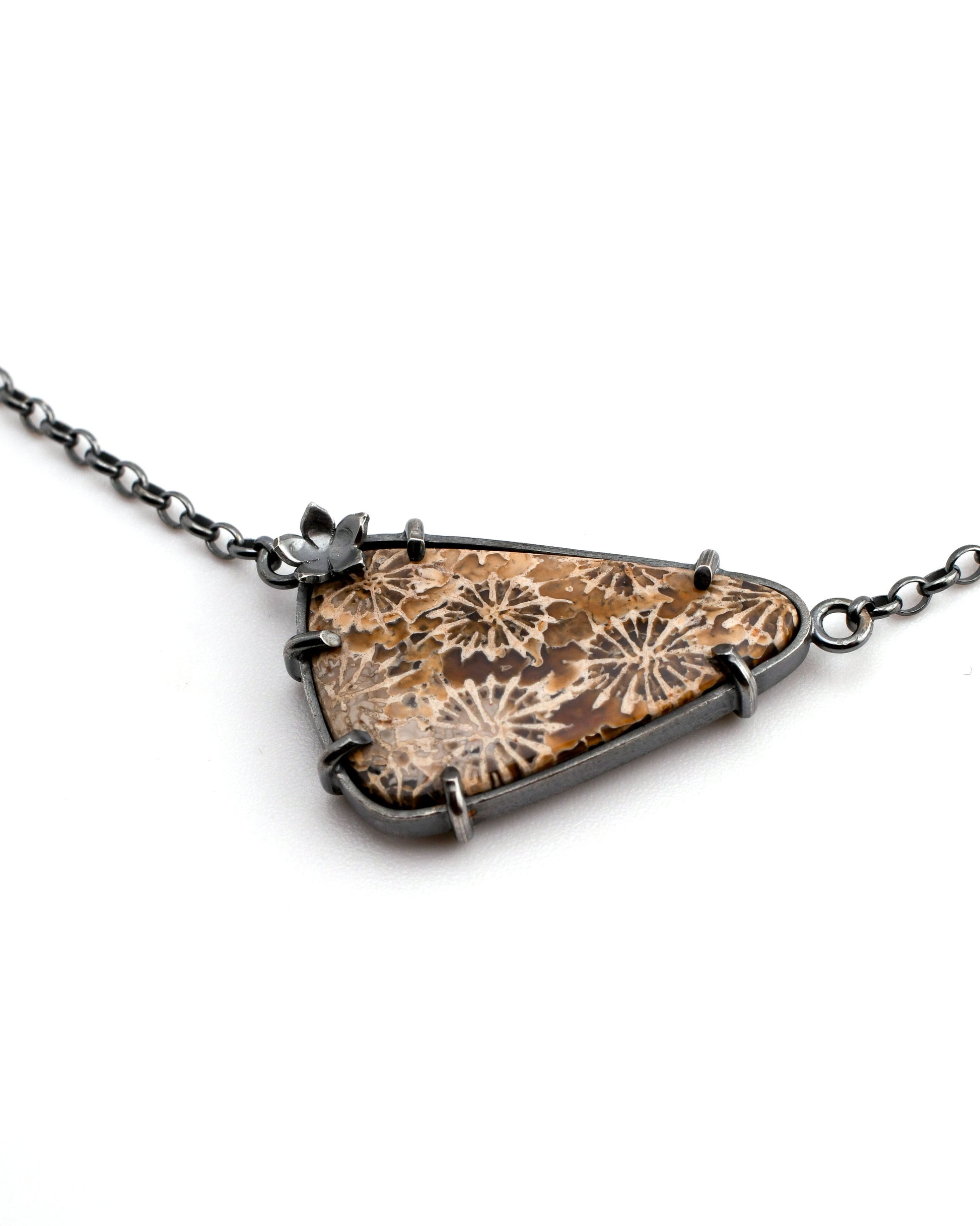 Necklace with a triangular fossil coral pendant featuring midnight blue and brown floral patterns on a white background