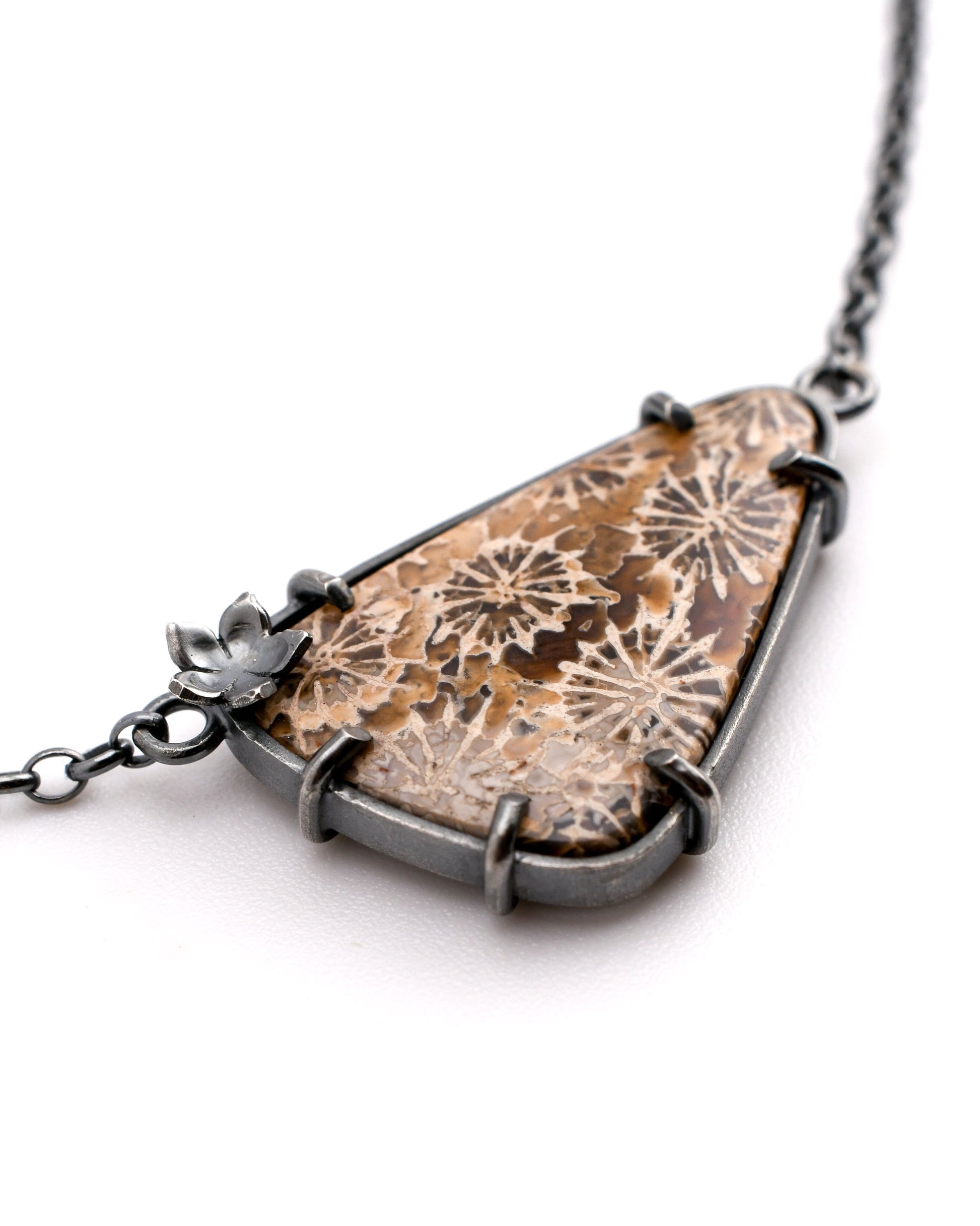 Necklace with a triangular pendant featuring floral patterns on a white background