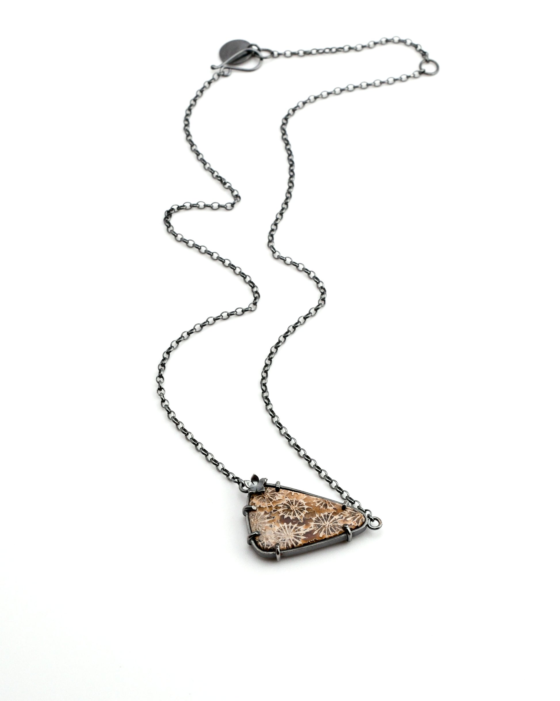 Necklace with a triangular fossil coral pendant in earth tones on a white background