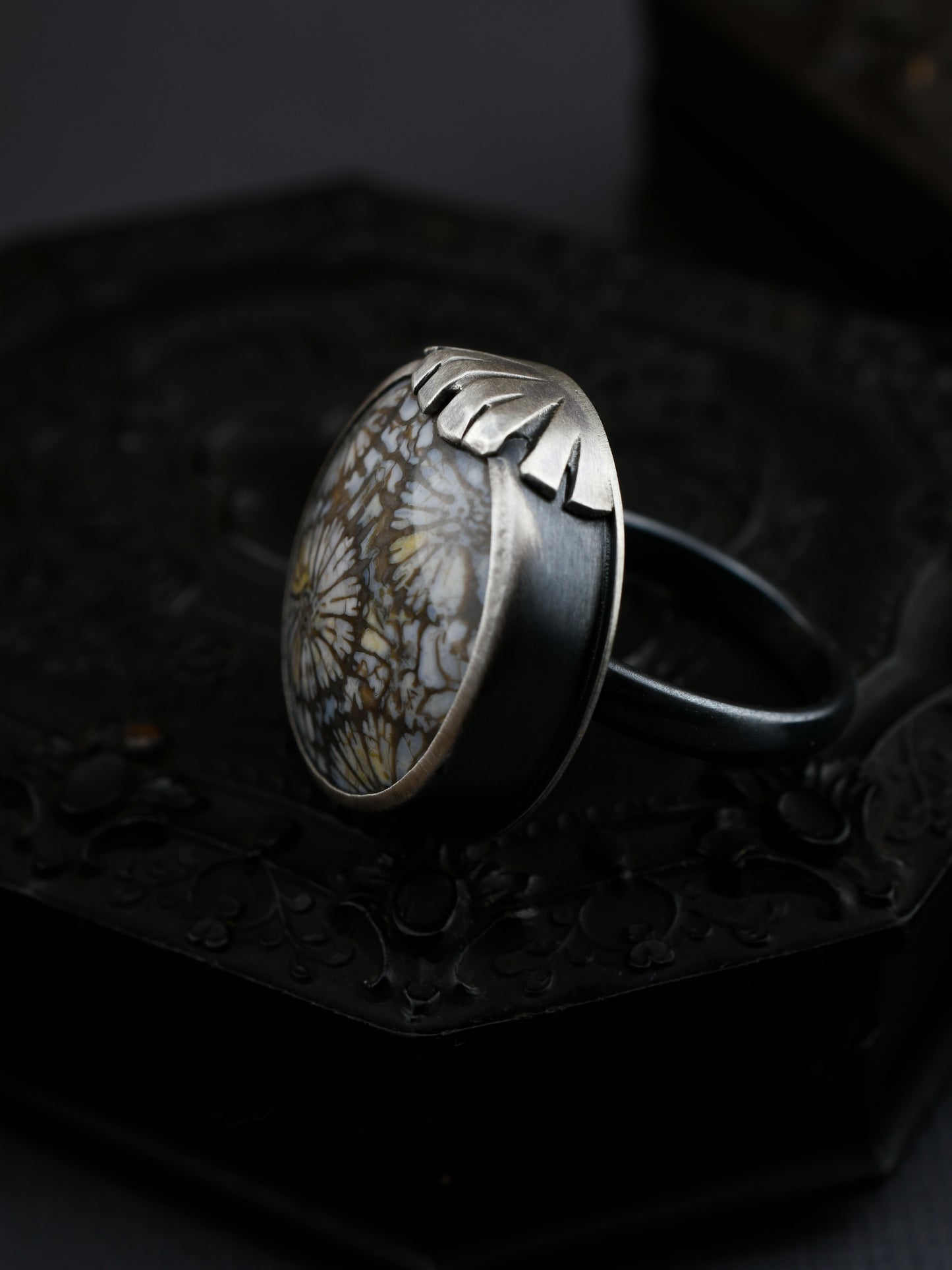 Silver ring with a natural stone on a dark textured surface