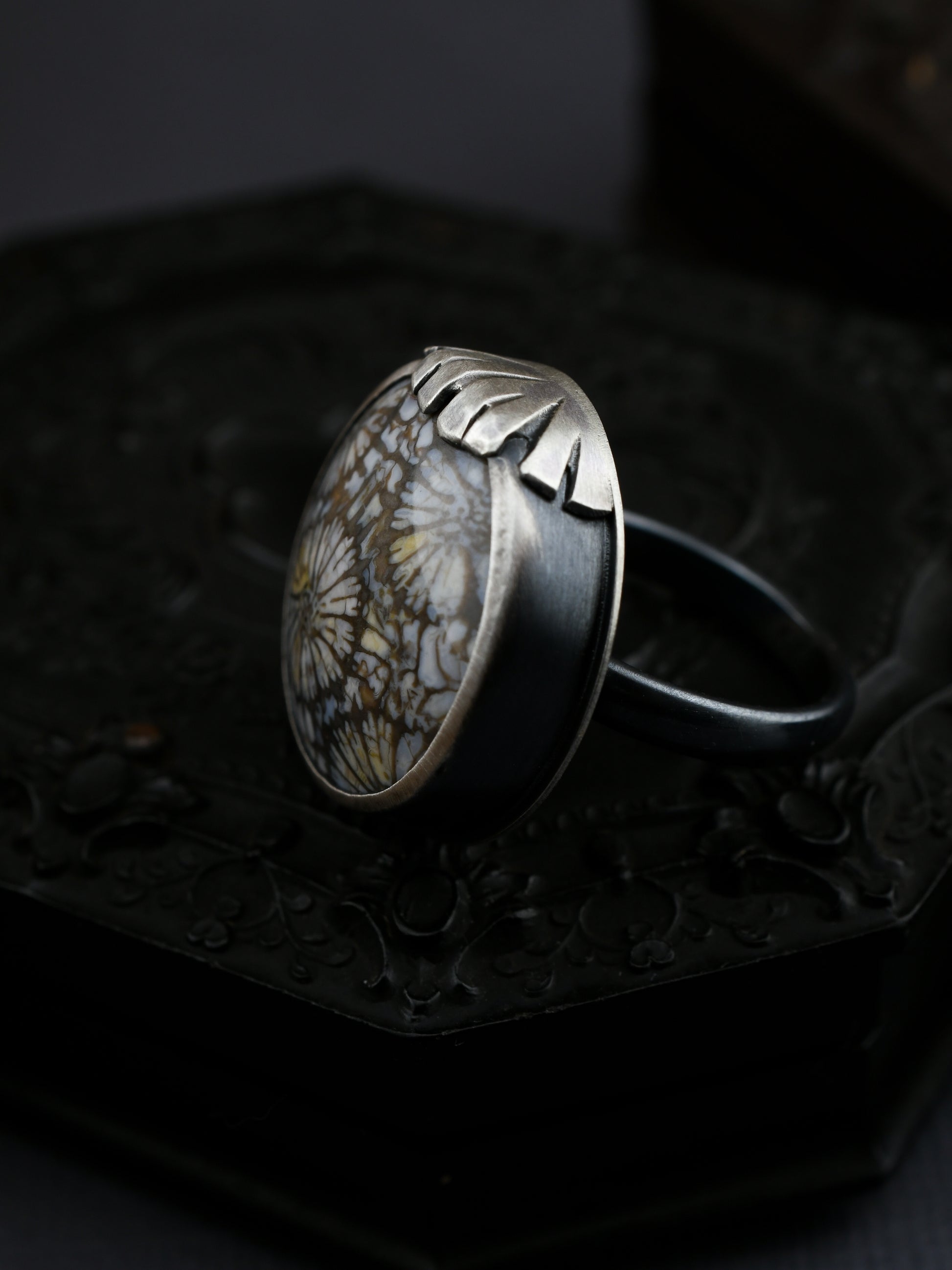Silver ring with a natural stone on a dark textured surface