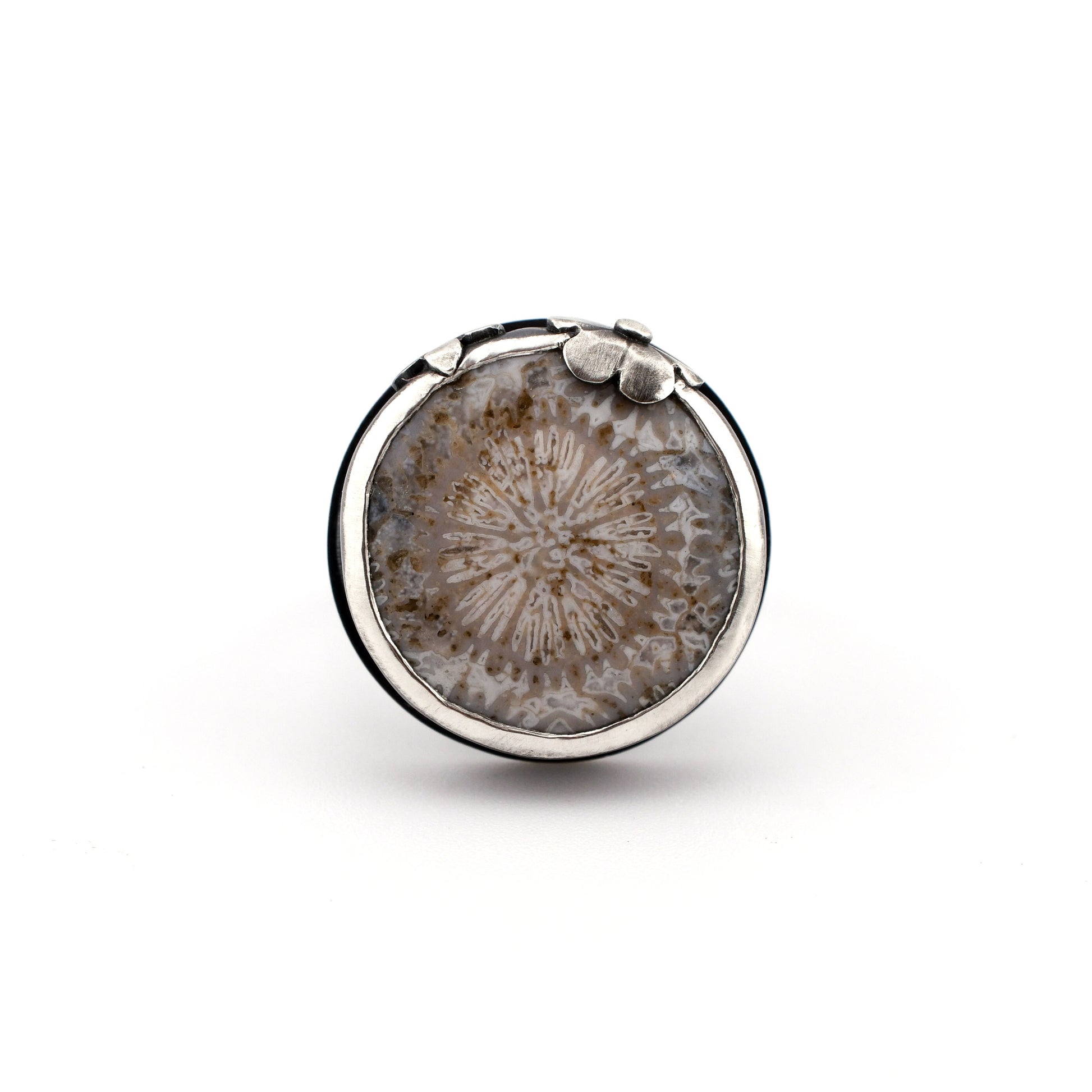 Round silver ring with a fossilized coral on a white background