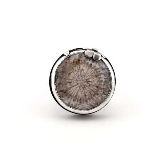 Round silver ring with a fossilized coral on a white background