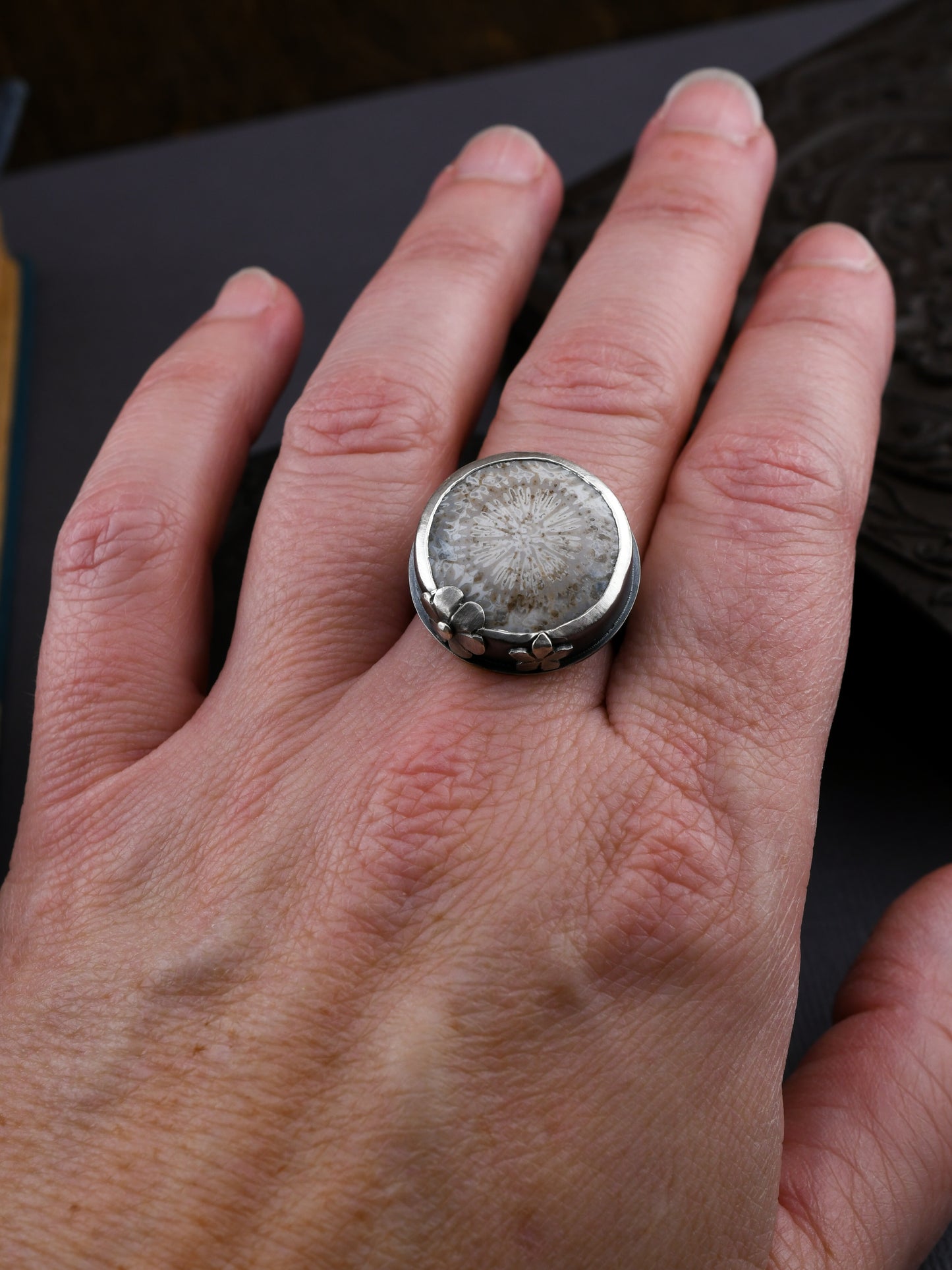 Close-up of a hand wearing a large silver ring with a textured stone.