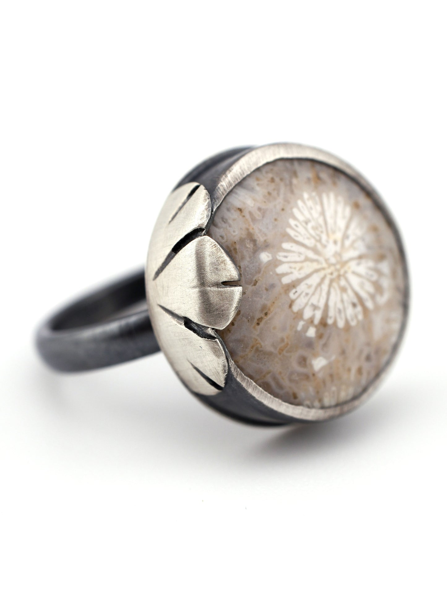 Silver ring with a fossilized coral and floral design on a white background