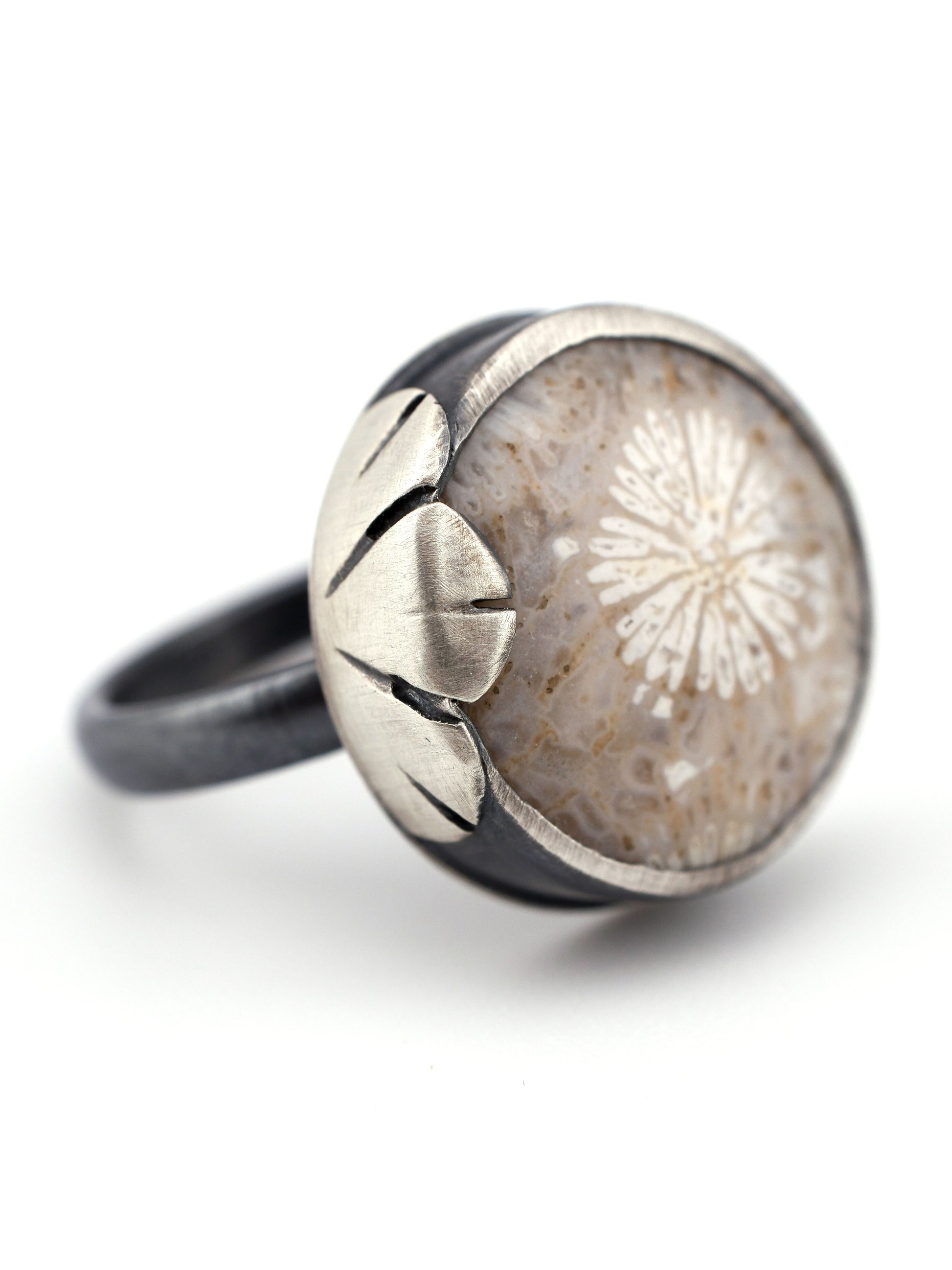 Silver ring with a fossilized coral and floral design on a white background