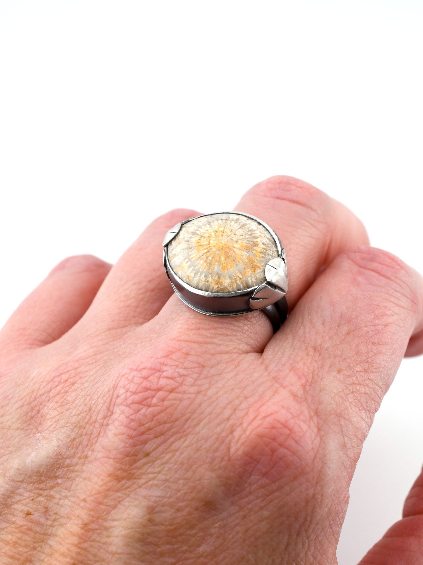 Hand wearing a ring with a floral design on a white background