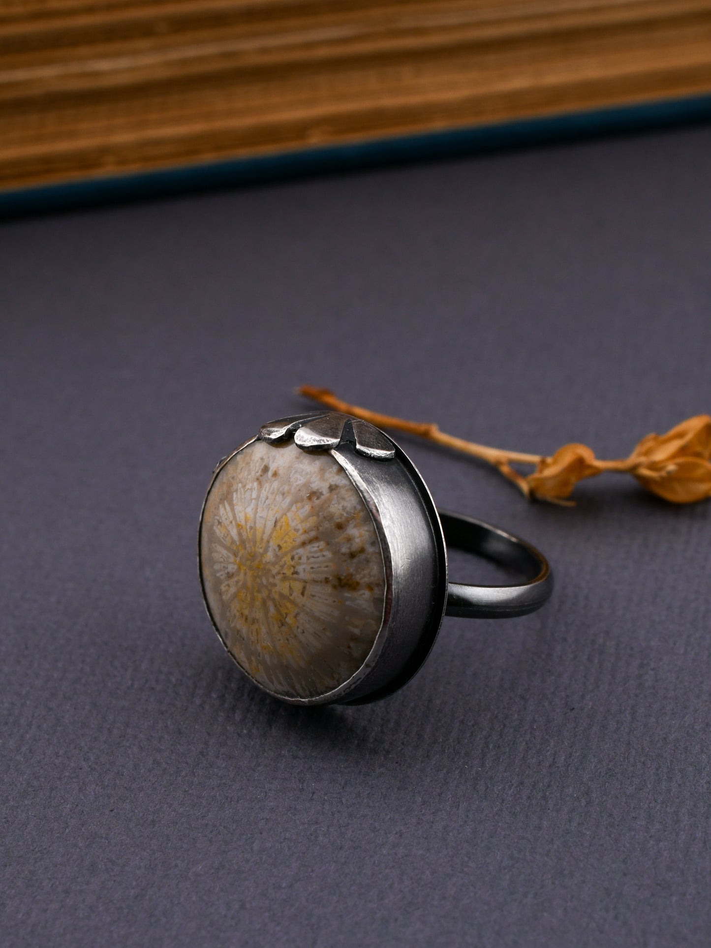 Silver ring with a textured stone on a dark surface