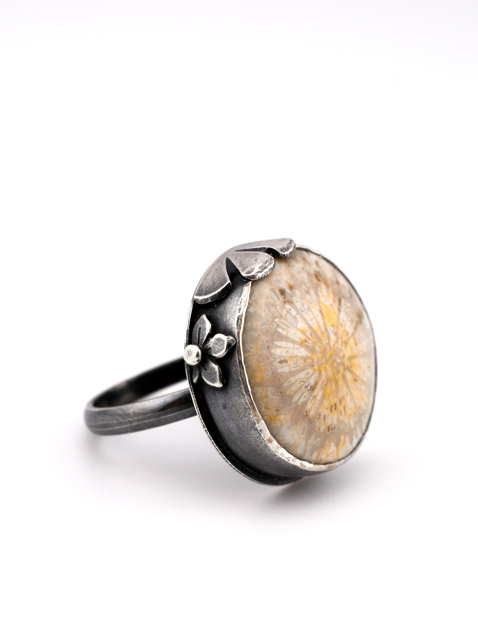 Silver ring with a floral design on a white background