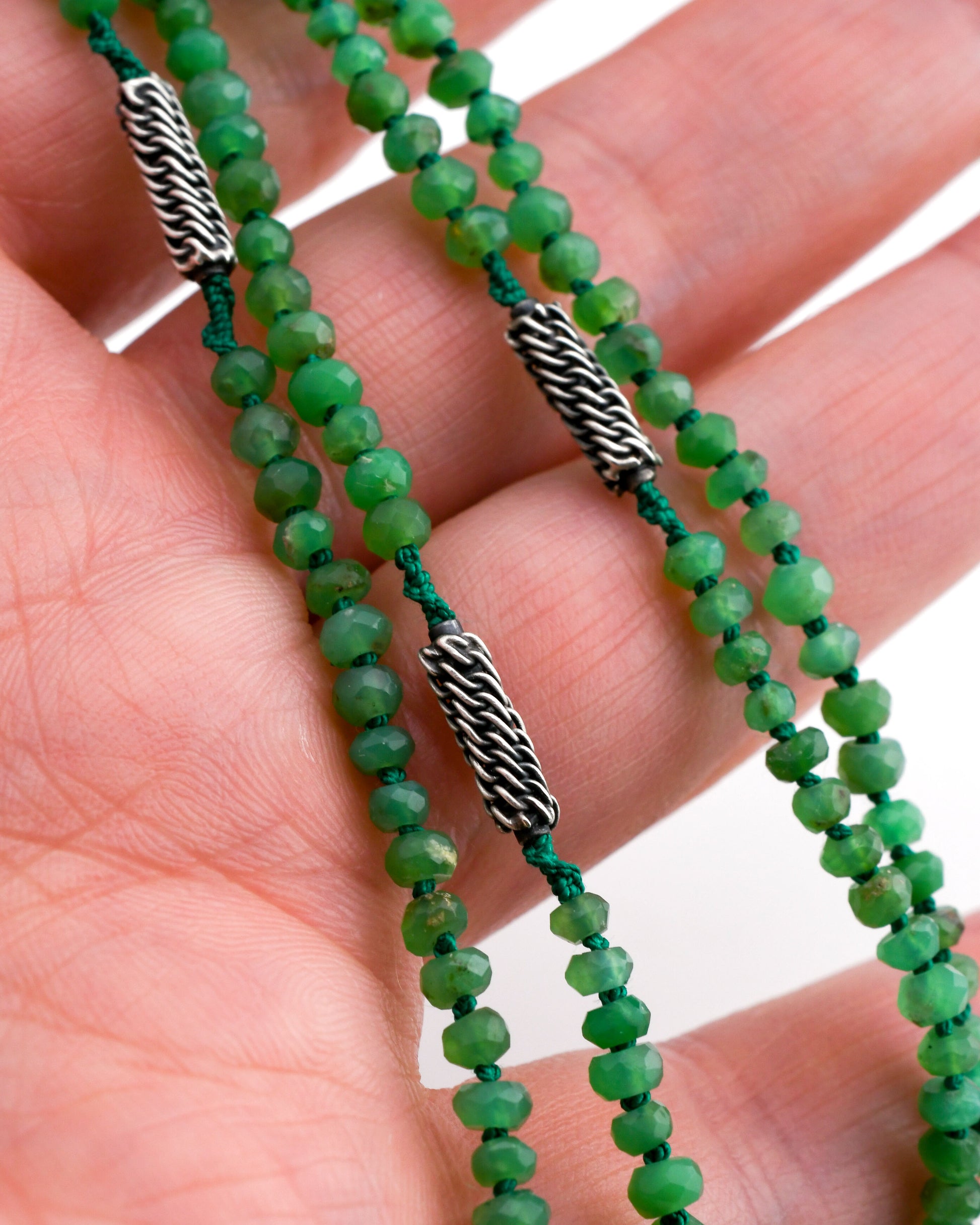 closeup of green chrysoprase beaded necklace with woven silver beads held in a hand