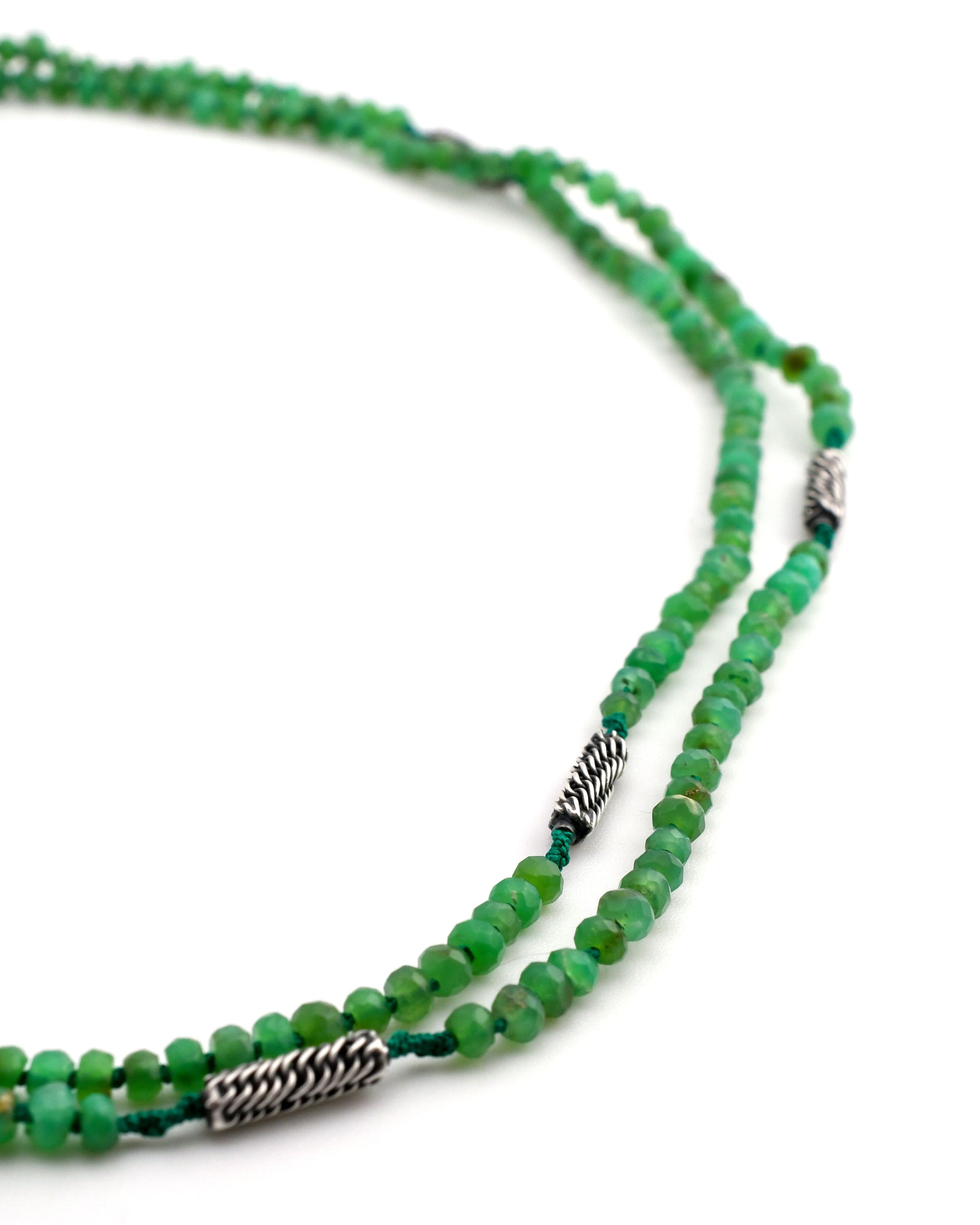 closeup of double strand green chrysoprase beaded necklace on green silk with woven silver bead accents on a white background