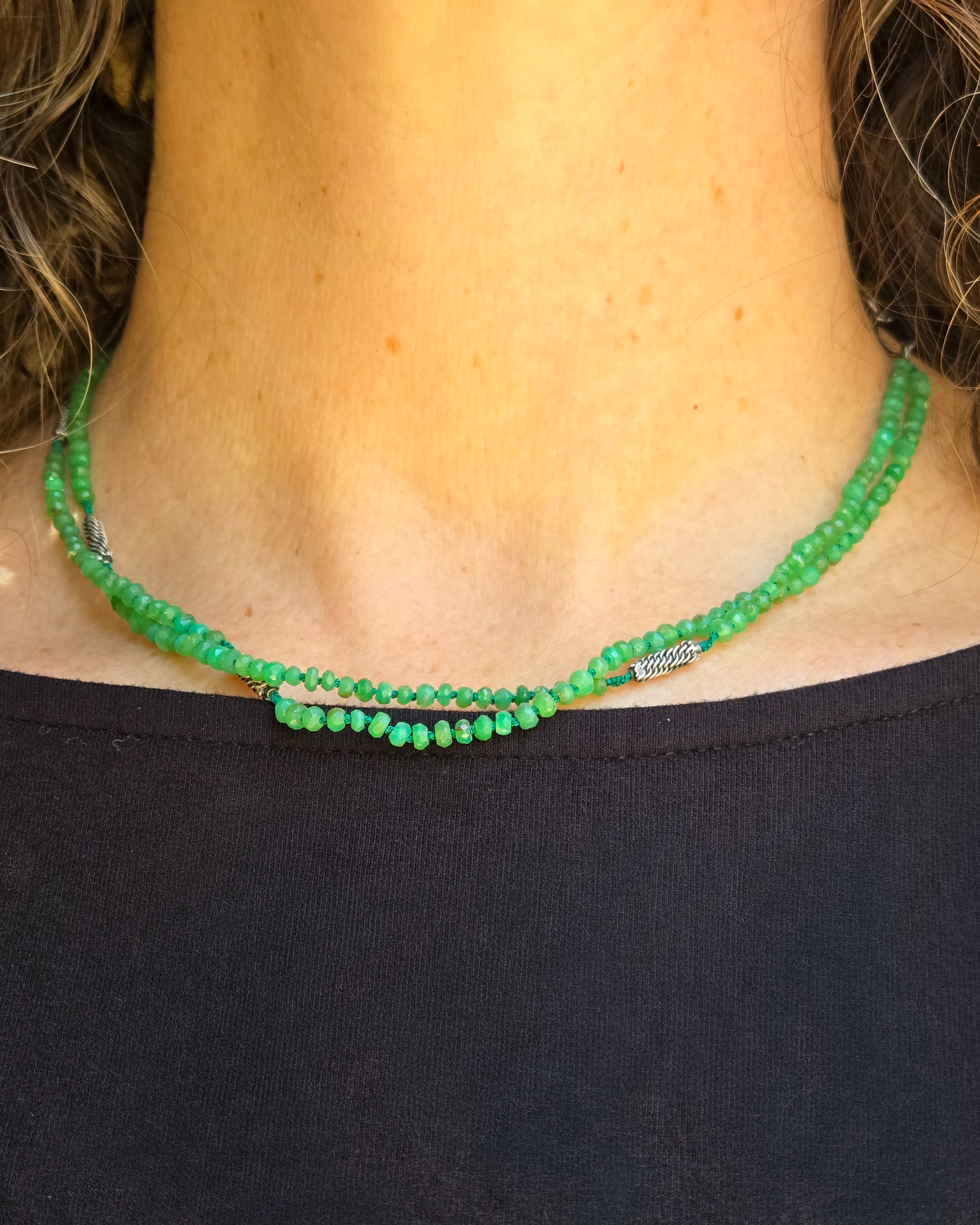 Green beaded necklace worn on a person wearing a black top 