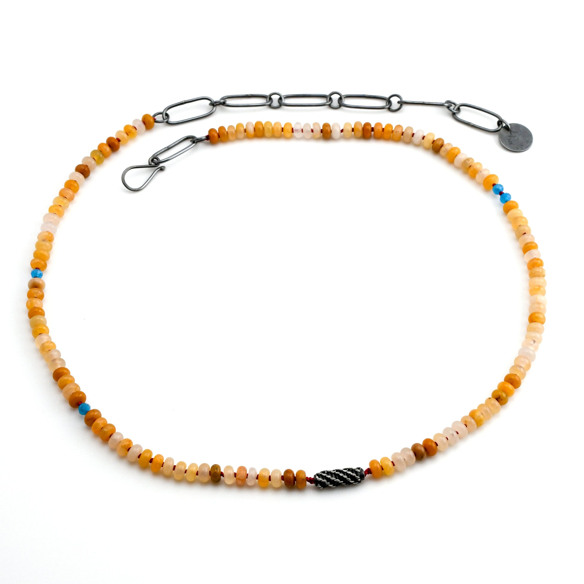 yellow jade beaded necklace with blue apatite bead accents, a woven silver bead and blackened chain on a white background